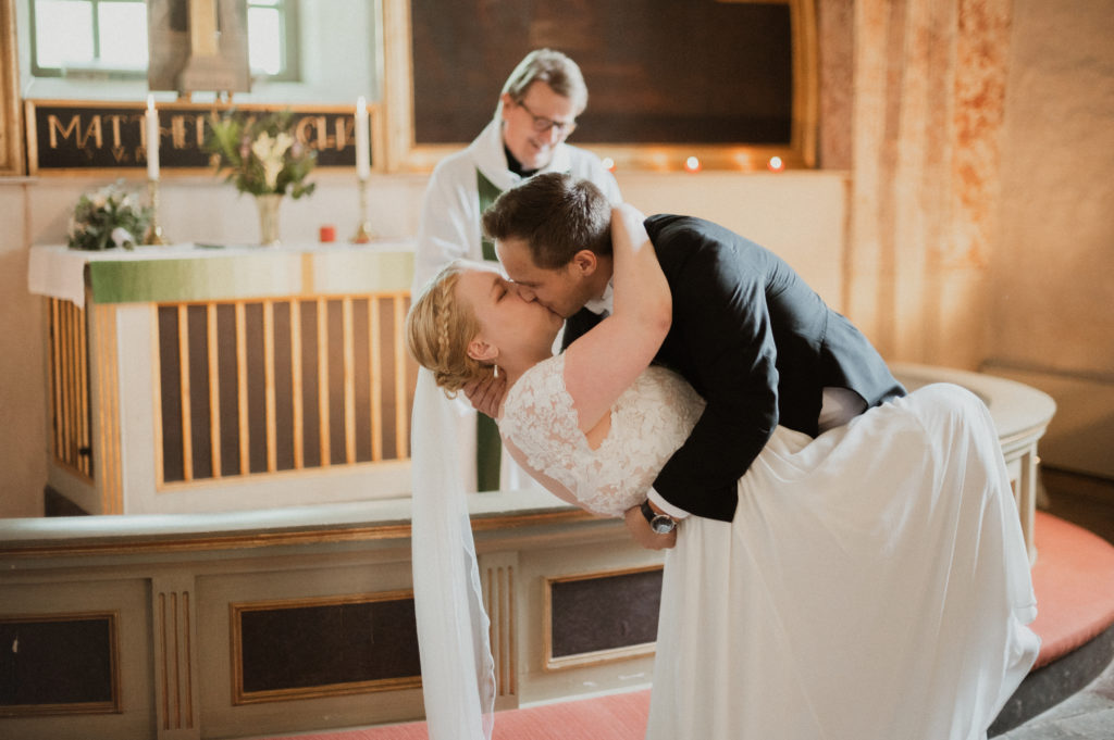 Brudparet kysser varandra framme vid altaret, Fotograf JD