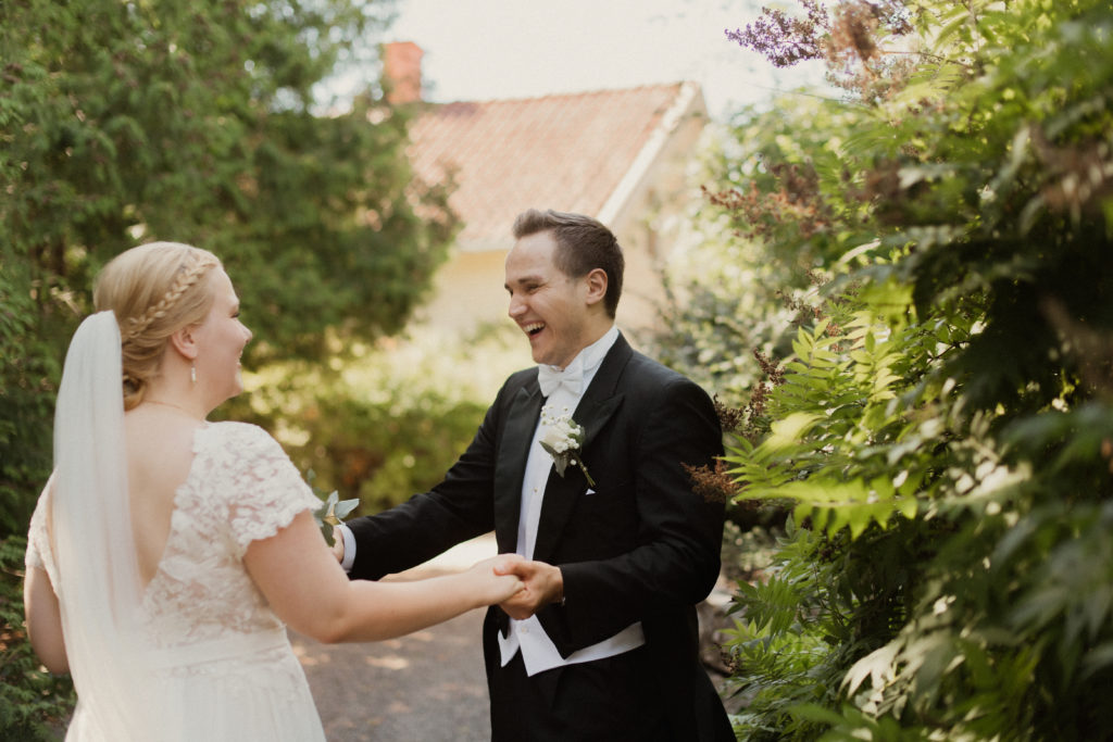Brudparet håller varandra i händerna och skrattar, Fotograf JD