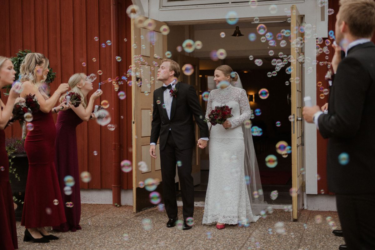 Bild på brudparet som går ut bland gästerna som blåser såpbubblor, Fotograf JD